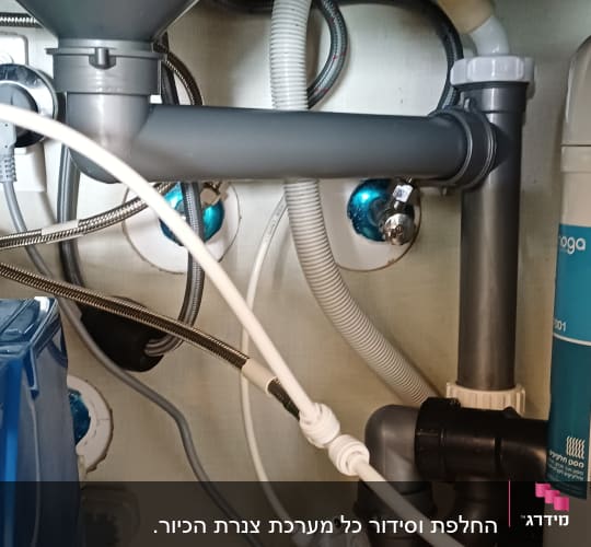 צנרת מתחת לכיור עם חיבורים וצינורות פלסטיק